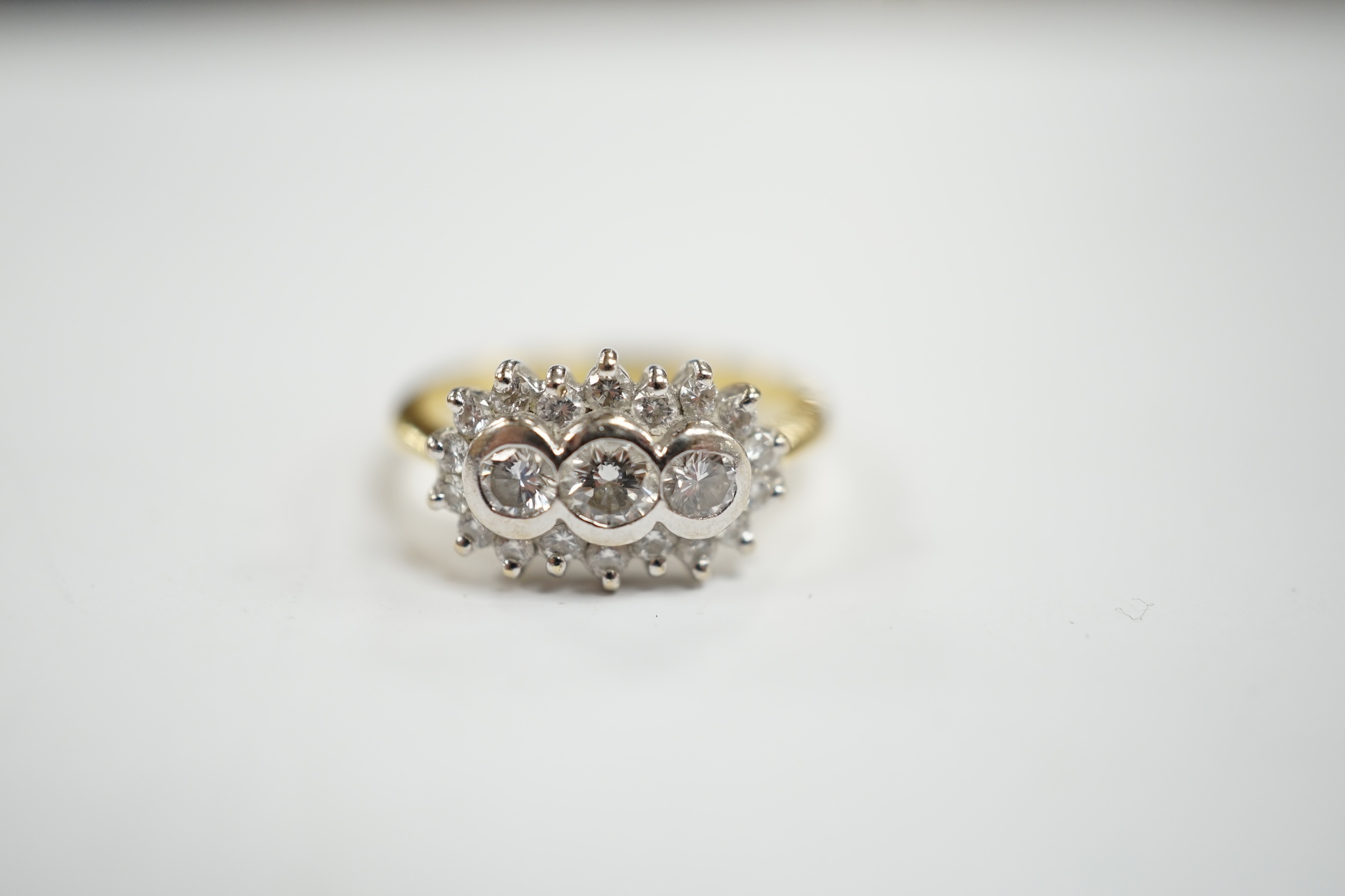 A modern 18ct gold and collet set three stone diamond ring, with diamond chip set border, size J/K, gross weight 4.6 grams.